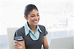 Smiling businesswoman doing online shopping through laptop and credit card