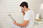 Side view of a man drinking coffee while reading newspaper in bed