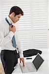 Side view of a businessman wearing tie while using laptop at a hotel room