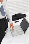 Side view mid section of a businessman using laptop at a hotel room