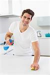 Portrait of a smiling young man cleaning kitchen counter in the house
