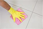 Close up of yellow gloved hand with cleaning rag wiping the floor at home