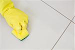 Close up of yellow gloved hand with sponge cleaning the floor at home