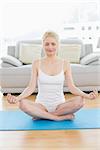 Toned young woman sitting in lotus pose with eyes closed at fitness studio