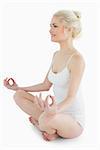 Full length of a toned young woman sitting in lotus position against white background