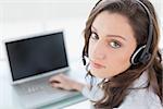 Close up portrait of a serious businesswoman wearing headset in front of laptop in office