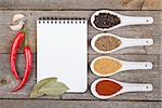 Colorful herbs and spices selection. Aromatic ingredients on wood table with blank notepad copyspace