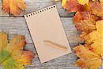 Blank page and colorful autumn maple leaves on wooden table background