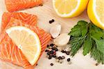 Salmon on cutting board with lemons and herbs. Closeup