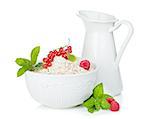 Fresh oat flakes with berries and milk jug. Isolated on white background