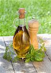 Olive oil bottle, pepper shaker and herbs on wooden table