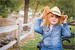 Cute Smiling Young Girl Wearing Cowboy Hat Posing for a Portrait Outside.