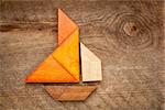 abstract picture of a sailing boat built from seven tangram wooden pieces over a rustic  barn wood, artwork created by the photographer