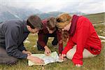 Group of young people are searching the destination on a map in the mountains