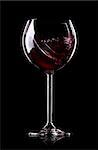 Wave of wine in wineglass on black background