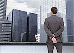 Composite image of businessman standing with hands behind back on the roof of building watching the city