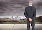 Composite image of serious businessman posing in front of dark landscape