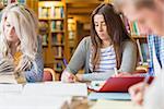 Group of students writing notes at desk in the college library