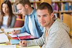 Group portrait of students writing notes at desk in the college library