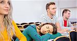 Young college students sitting in the classroom with one asleep girl