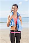 Portrait of a beautiful smiling healthy woman with towel around neck standing on beach