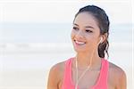 Close up of a smiling healthy woman with earphones on beach