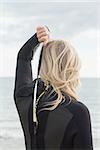 Rear view of a young blond in wet suit standing at the beach