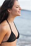 Close up side view of a cute young woman with eyes closed at the beach