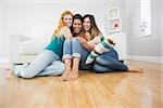 Portrait of happy young female friends embracing on floor against sofa at home