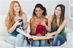 Portrait of happy young female friends with pizza and wine on sofa at home
