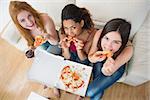 Overhead portrait of happy young female friends with pizza and wine on sofa at home