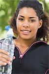 Close up portrait of a tired healthy young woman with water bottle in the park