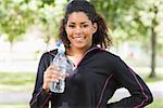 Portrait of a smiling healthy young woman with water bottle in the park