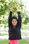 Portrait of a healthy young woman stretching her hands during exercise at the park