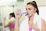 Close up of a young woman drinking water in the gym