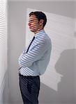 Side view of a young businessman peeking through blinds in office