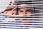 Close up portrait of a young businessman peeking through blinds