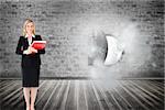 Composite image of attractive blonde businesswoman smiling and holding folders