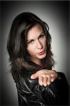 Portrait of a dark haired pretty woman in black leather jacket which gives a kiss on the hand