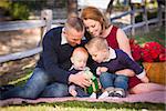 Beautiful Small Young Family Opening Christmas Gifts in the Park.