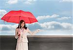 Composite image of happy brunette businesswoman holding umbrella