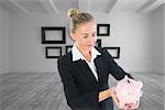 Composite image of blonde usinesswoman holding piggy bank