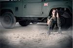 Woman Soldier Sitting on Ground by Military Vehicle