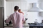 Man holding baby and making cup of coffee