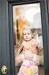 Man holding baby looking through front door