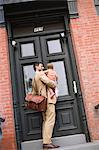Man holding baby standing at front door