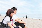 Young couple sitting on sandy beach