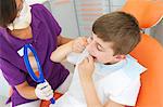 Dental hygienist holding hand mirror while patient flosses