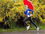 Teenage girl jogging with umbrella on road, Bainbridge Island, Washington, USA