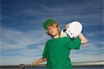 Portrait of boy holding skateboard over shoulder